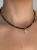 Zbliżenie na choker MAMORI ze złotym hematytem i zawieszką Ręka Fatimy.