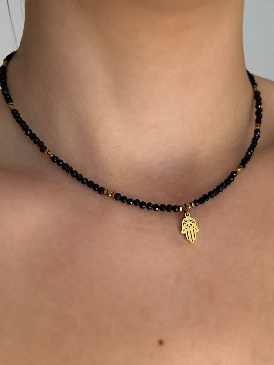 Zbliżenie na choker MAMORI ze złotym hematytem i zawieszką Ręka Fatimy.