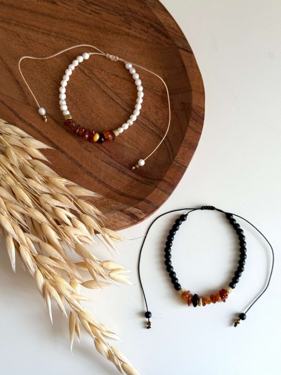 Bransoletki AMBER DAWN i AMBER DUSK – duet bursztynowych bransoletek handmade. AMBER DAWN z perłami na beżowym sznurku i AMBER DUSK z czarnymi kamieniami na czarnym sznurku. Biżuteria inspirowana wschodem i zachodem słońca.