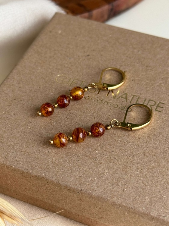 Zbliżenie na bursztyn i złoty hematyt w kolczykach TAWRA – naturalne kamienie w ciepłej tonacji