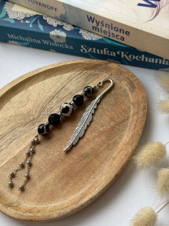 Artystyczne ujęcie zakładek MARCADOR z kamieniami naturalnymi na drewnianej podkładce obok książki.