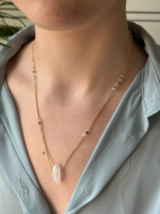 Talizman harmonii: złoty naszyjnik z naturalnym kryształem górskim marki Lazuri.