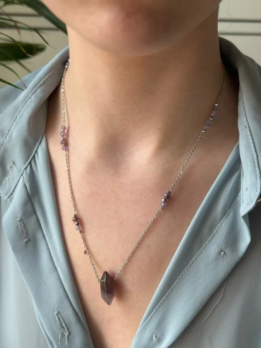 Srebrny naszyjnik KIMI z dużym fioletowym kryształem ametystu na błękitnej koszuli.