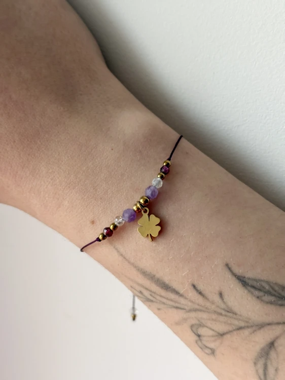 Bransoletka talizman na fioletowym sznurku z fasetowanymi kuleczkami fluorytu, ametystu i granatu.