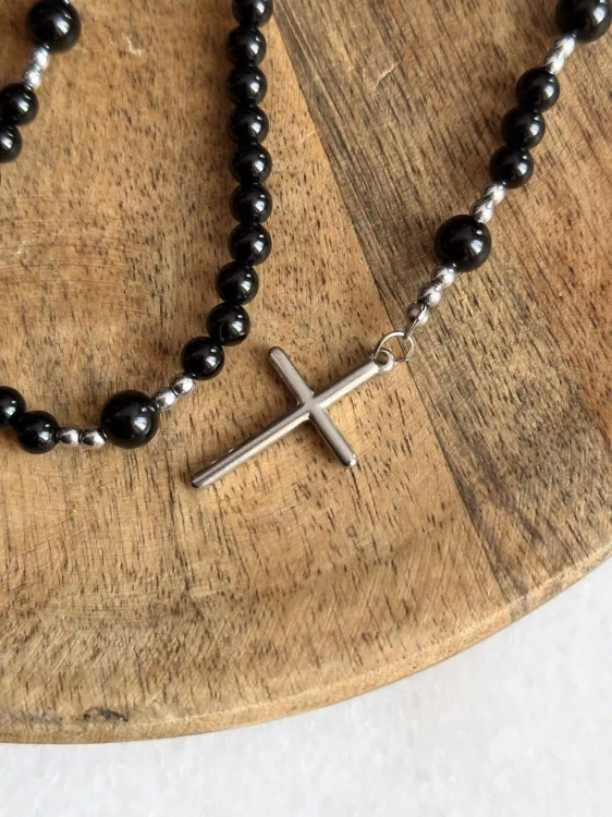Minimalistyczny srebrny krzyż ze stali chirurgicznej wieńczący różaniec z kamieni naturalnych.