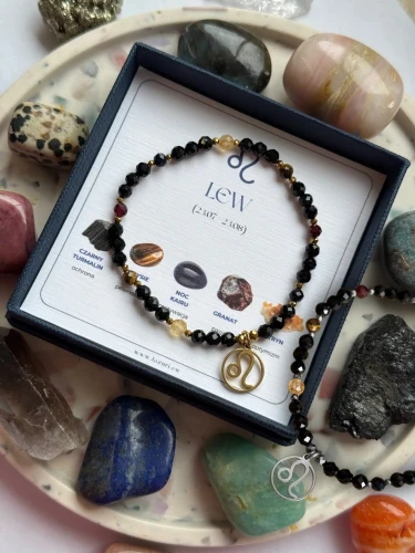 Dwie ochronne bransoletki zodiakalne Cosmic Aura dla Lwa z czarnym turmalinem: wersja ze złotym oraz srebrnym hematytem i zawieszką.