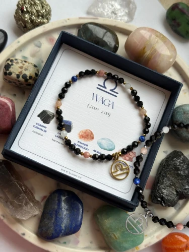 Dwie ochronne bransoletki zodiakalne Cosmic Aura dla Wagi z czarnym turmalinem: wersja ze złotym oraz srebrnym hematytem i zawieszką.