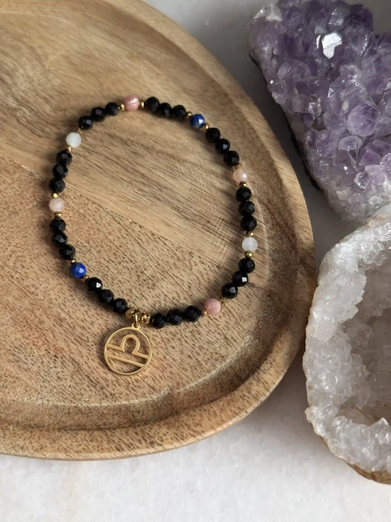 Artystyczne ujęcie bransoletki Cosmic Aura ze złotymi detalami, eksponujące diamentowy blask fasetowanych minerałów.