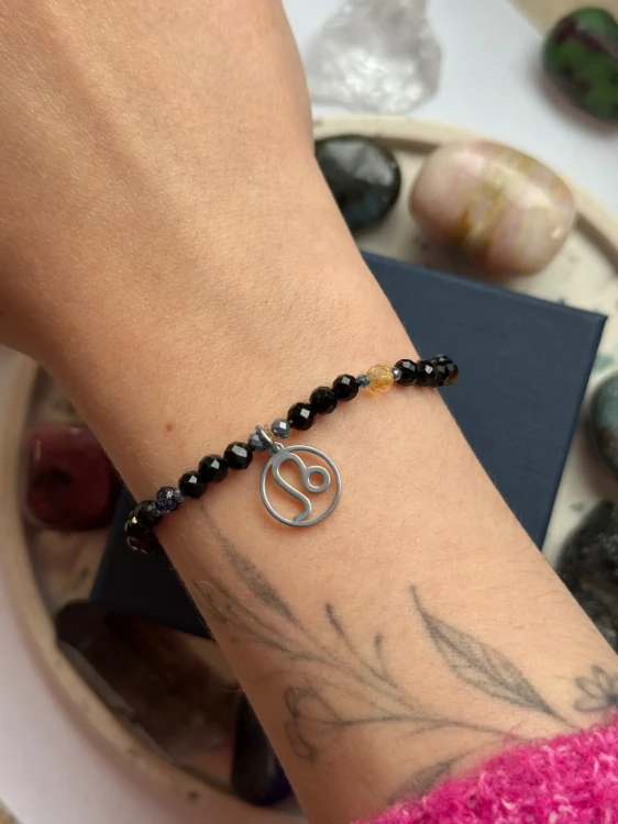 Ochronna bransoletka dla Lwa ze srebrną zawieszką zodiakalną na nadgarstku modelki.