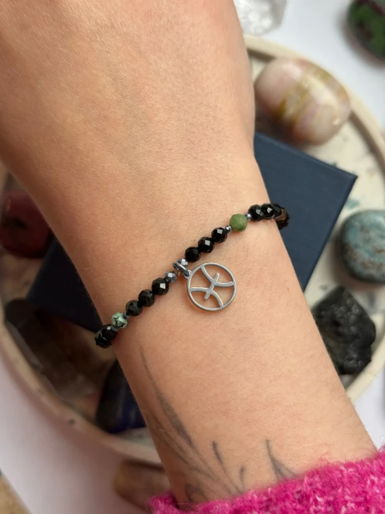 Ochronna bransoletka dla Ryb ze srebrną zawieszką zodiakalną na nadgarstku modelki.