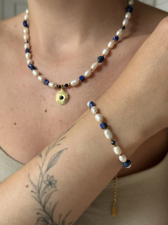 Kobieta nosząca pasujący zestaw handmade: naszyjnik z zawieszką słońca oraz bransoletkę z lapis lazuli i pereł.
