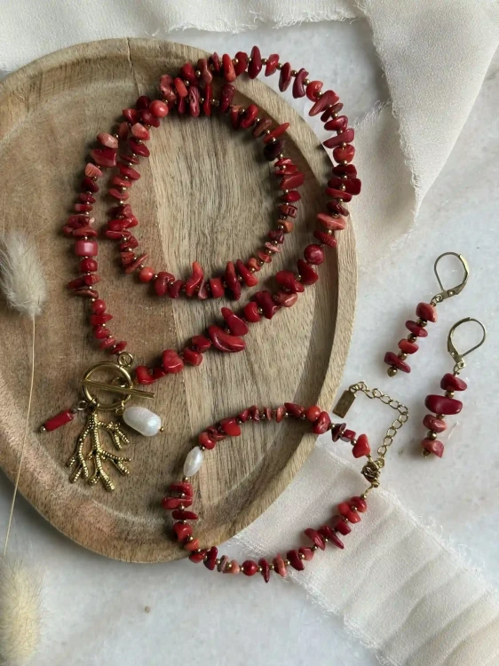 Ekskluzywny komplet biżuterii handmade Lazuri z czerwonego korala i pereł: naszyjnik z zawieszkami, regulowana bransoletka oraz wiszące kolczyki na drewnianej tacy.