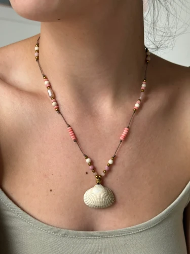 Kobieta nosząca naszyjnik z muszelką wyregulowany jako krótki choker blisko szyi.