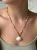 Kobieta nosząca naszyjnik z muszelką wyregulowany jako krótki choker blisko szyi.