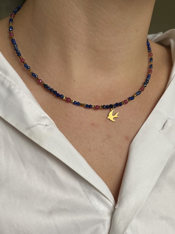 Złota jaskółka na tle intensywnie niebieskich kamieni lapis lazuli – detal SVELGE.
